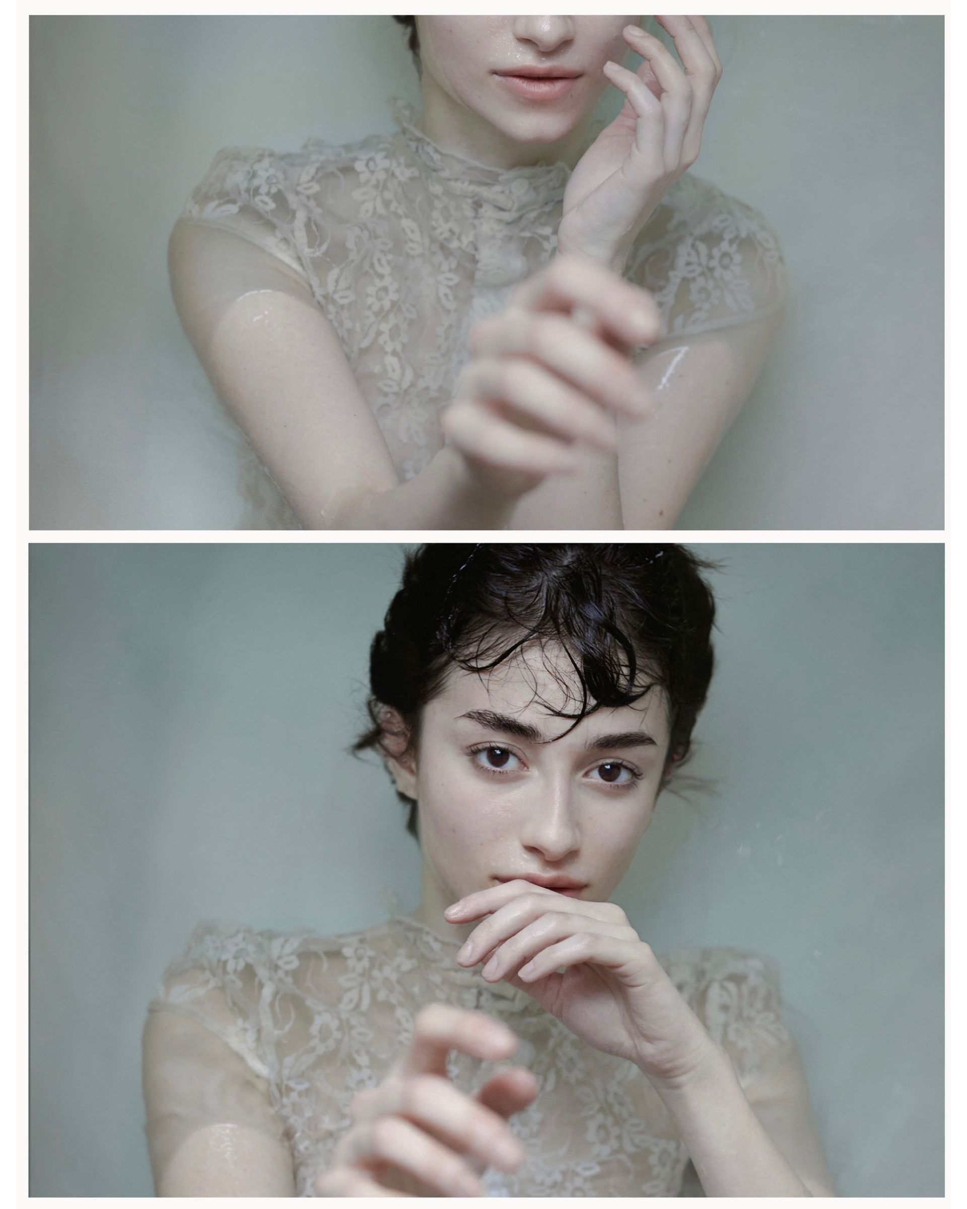 Woman in lace top submerged in water, hands near face, gazing towards camera.