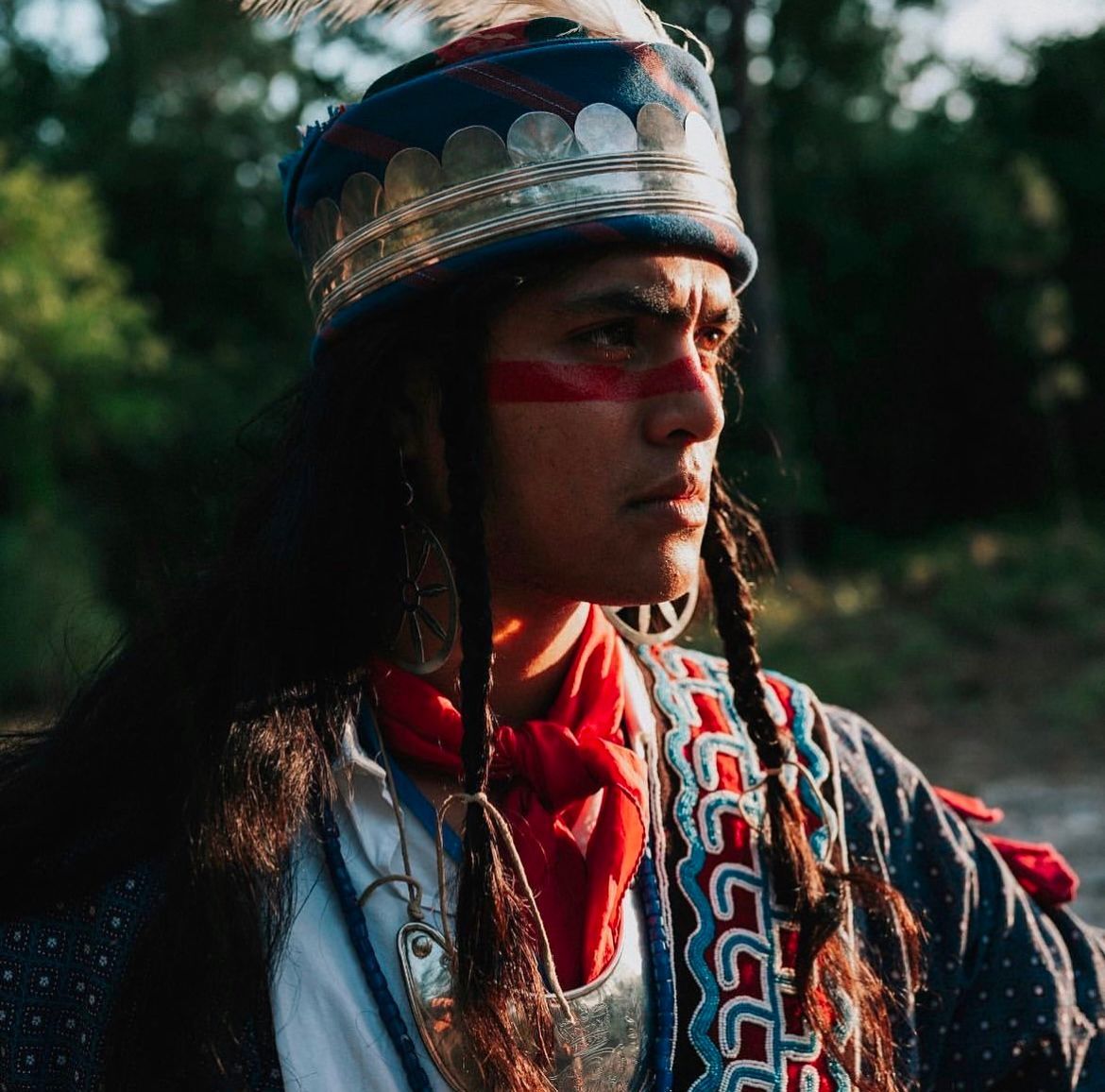 Person wearing a blue, gold-trimmed headdress and red face paint.