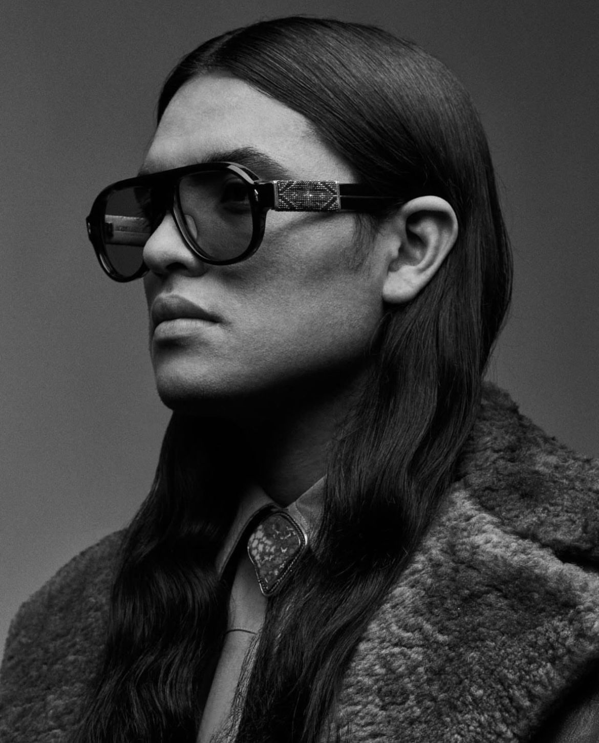Person wearing large sunglasses and fur coat, looking to the side.