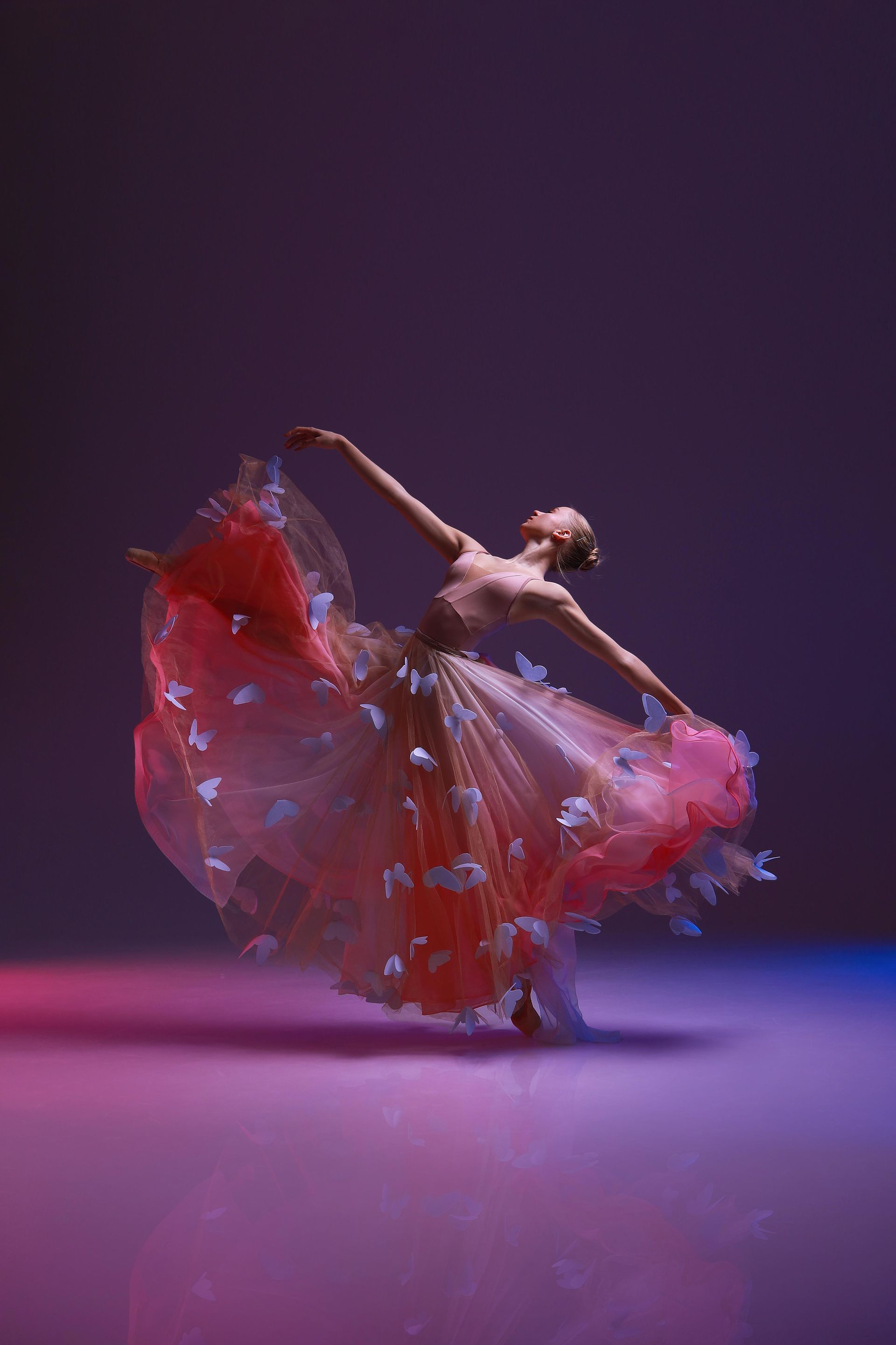 Ballerina in pink dress with butterflies, arms outstretched, dancing on a gradient purple/blue stage.