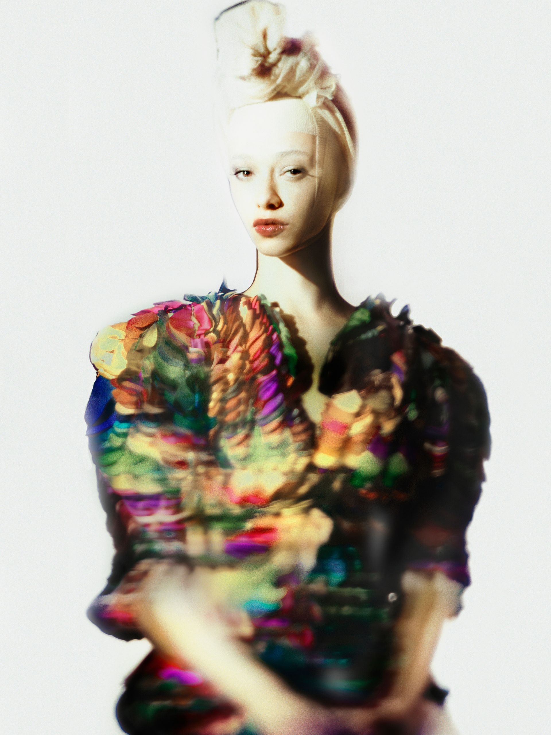 Woman with pale skin, intricate colorful bodice, and high blonde hair.