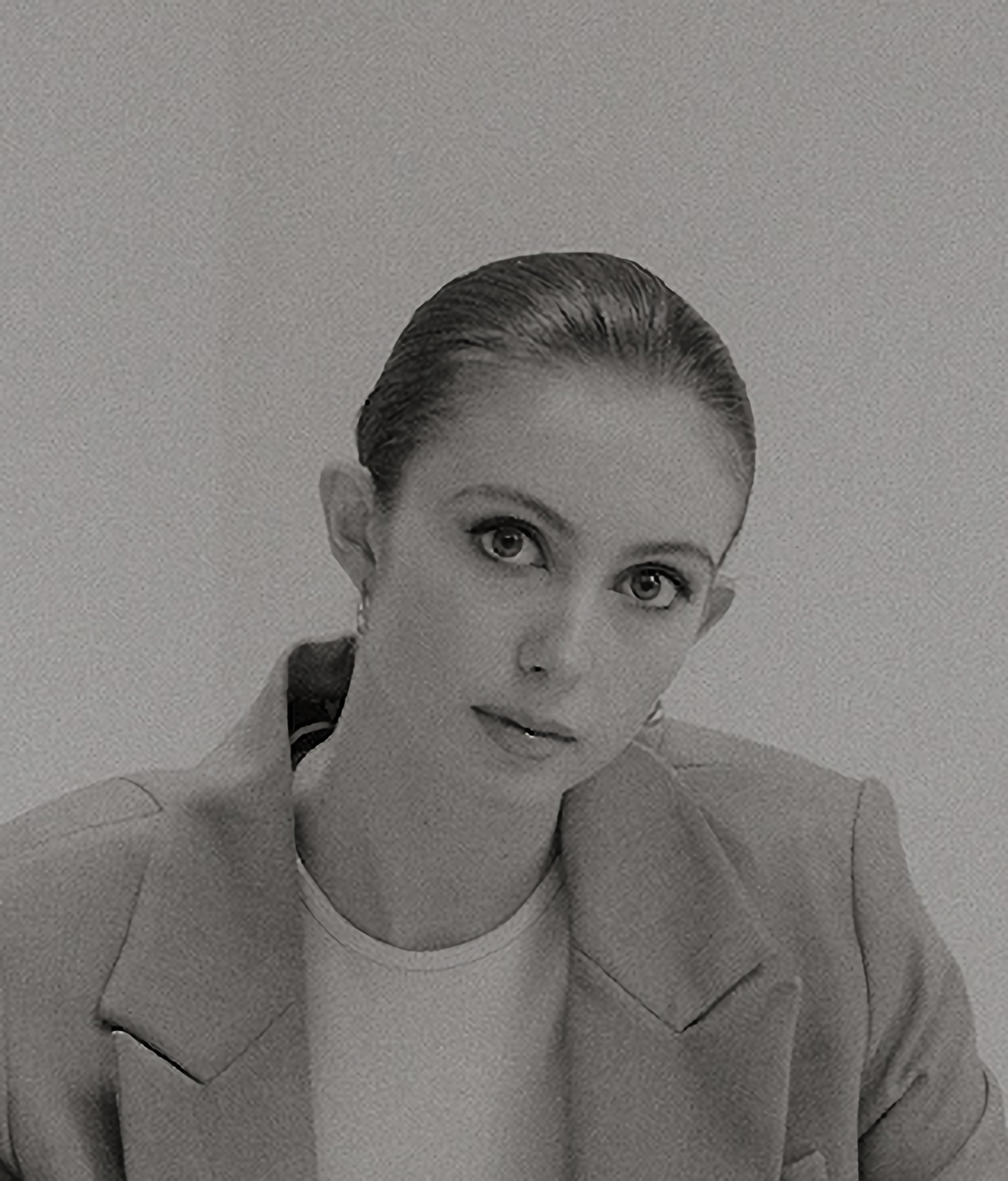 Woman in a blazer, looking at the viewer. Hair pulled back. Black and white.