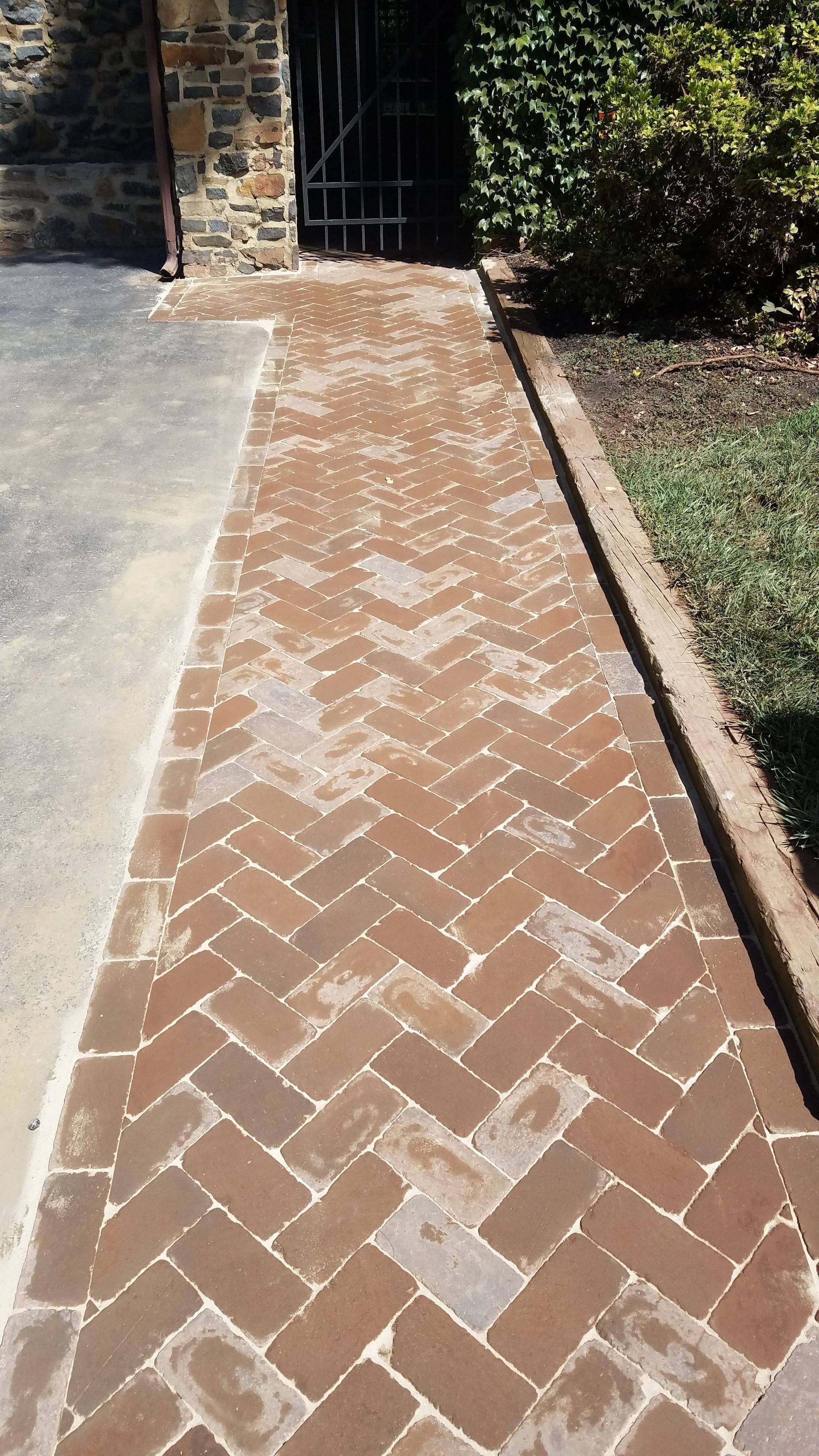 Brick pathway in herringbone pattern leading to a gate and entrance.