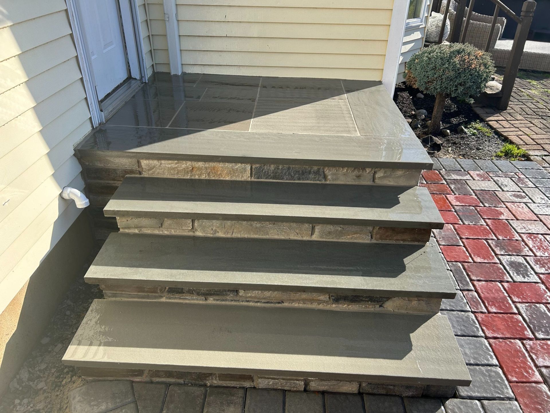 Stone steps leading to a house entrance, with brick accents and a tiled landing.