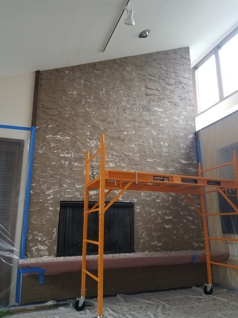 Fireplace with textured surface and scaffolding; room being renovated.