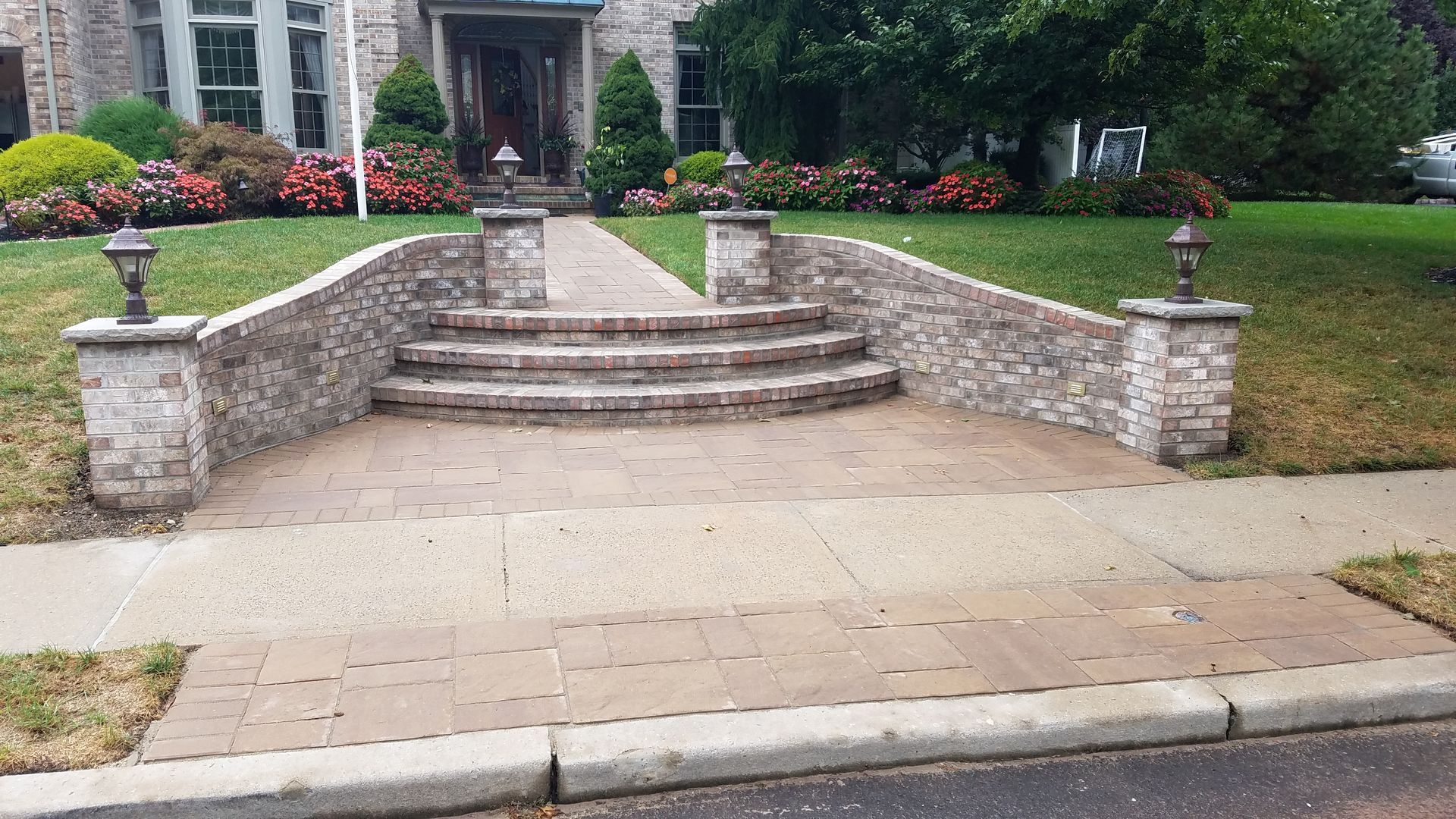Stone steps leading to a house, with a brick wall and landscaping.