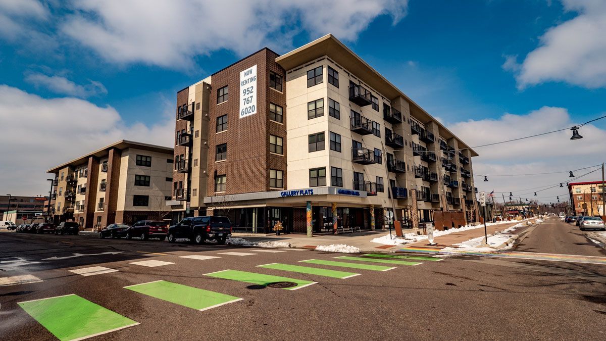 A large apartment building with a green crosswalk in front of it.