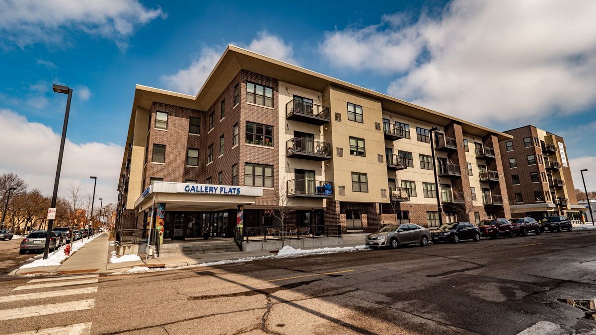 A large apartment building with cars parked in front of it.