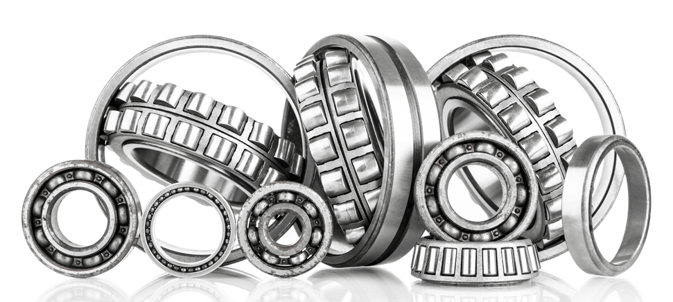 Rodamientos de bolas metálicos de distintos tamaños están dispuestos sobre una superficie blanca.