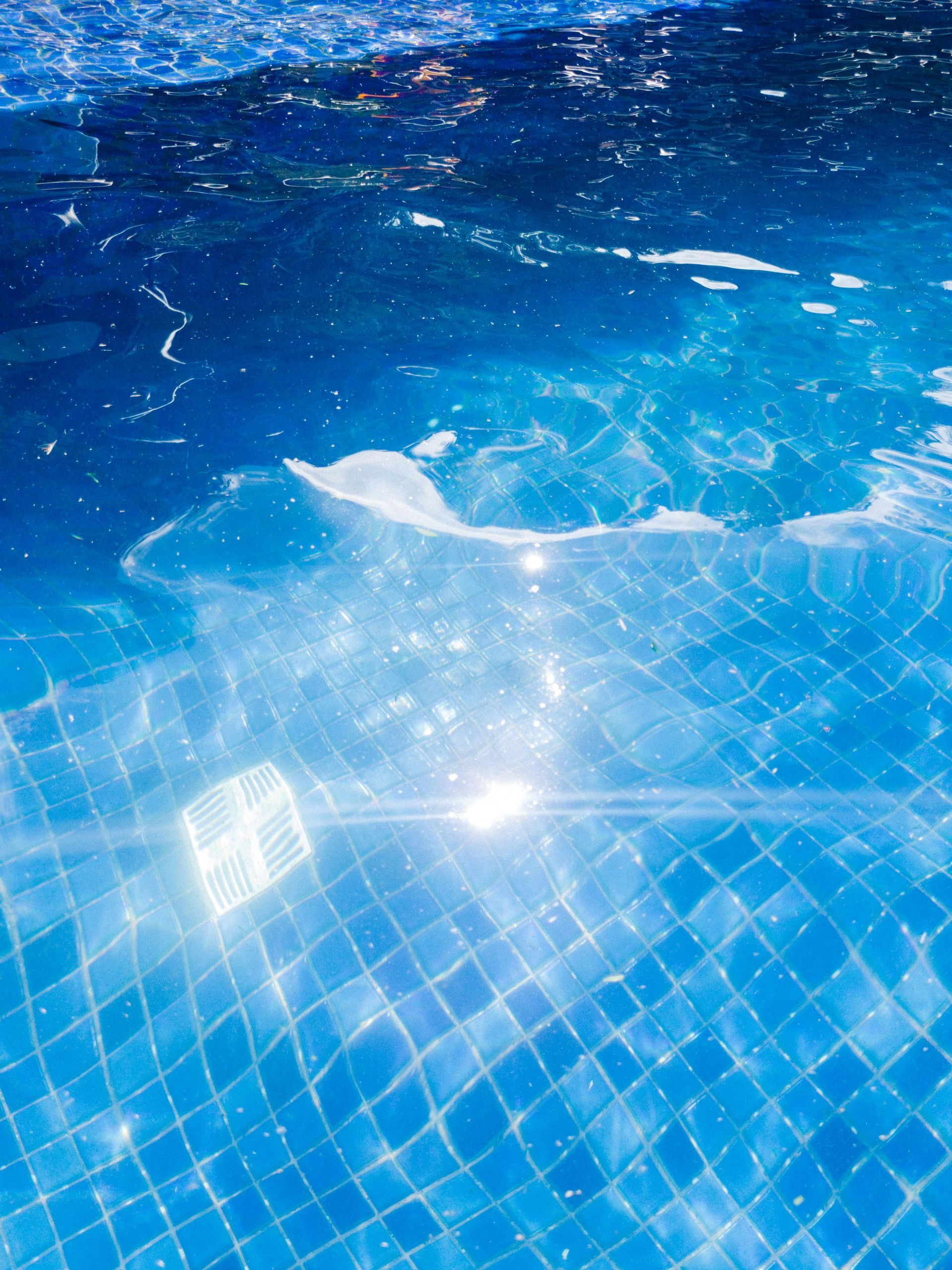 Blue pool water with sunlight reflections on a tiled surface