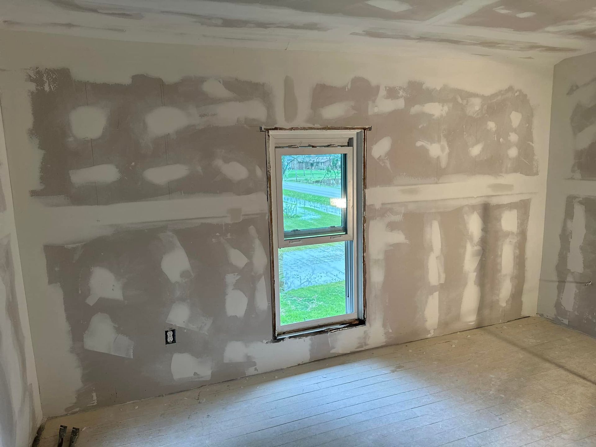 A room with drywall walls and a window in it.