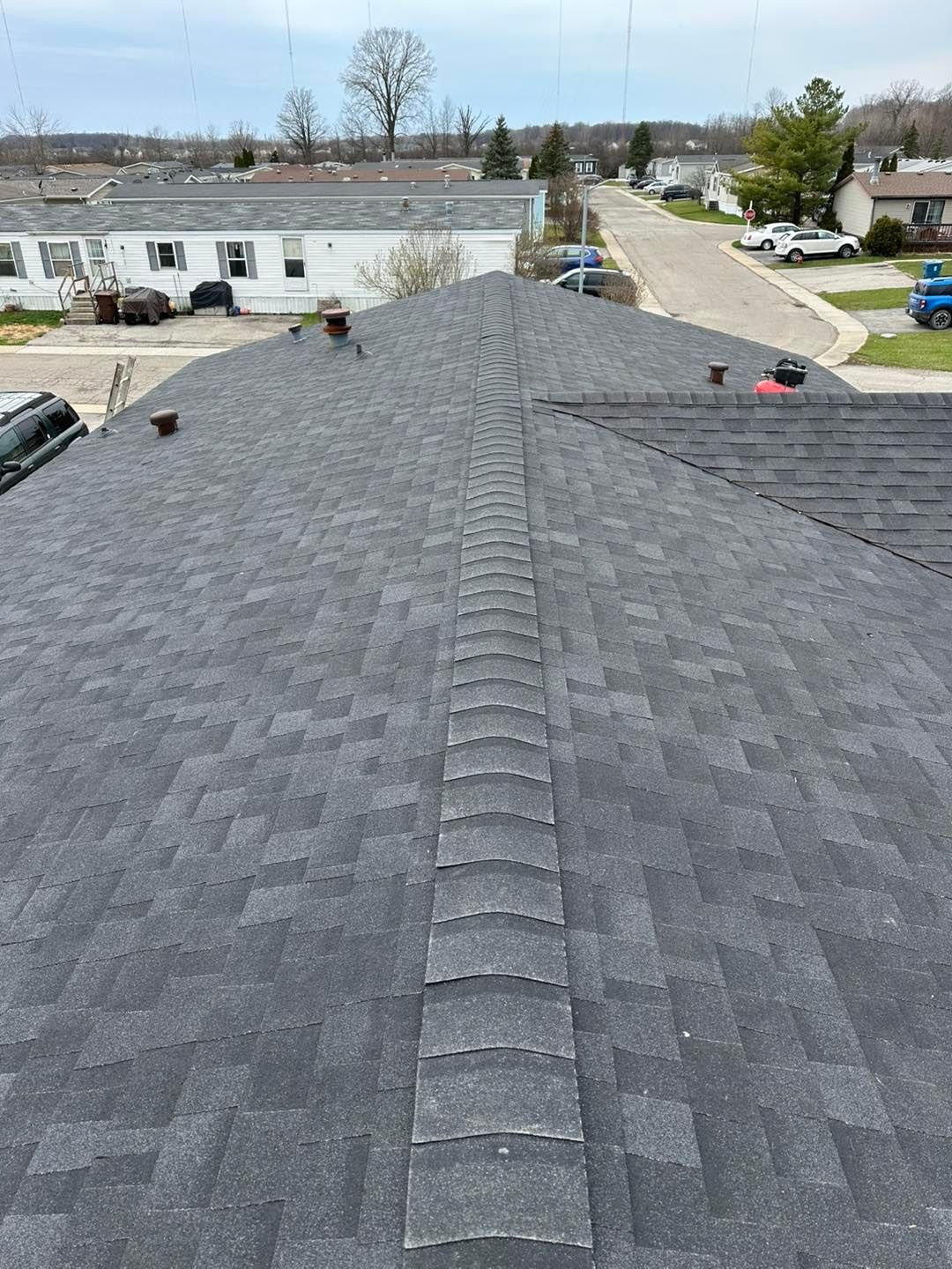 A roof with a row of shingles on it is being installed on a house.