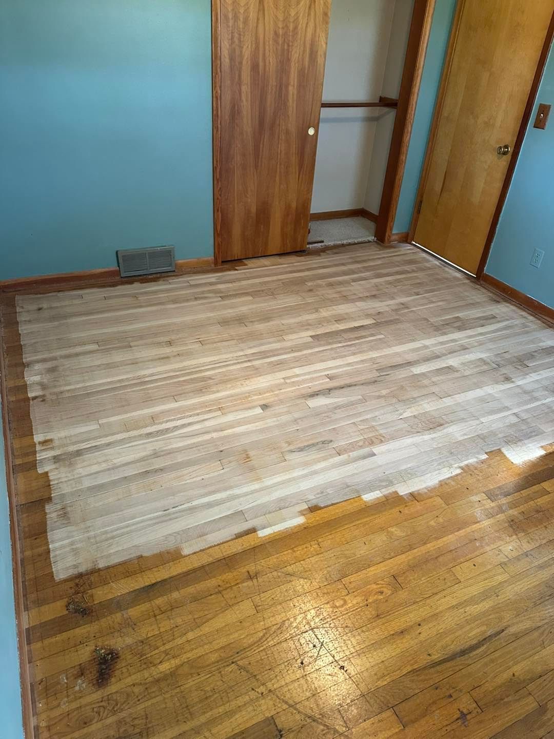 A wooden floor is being painted in a room.