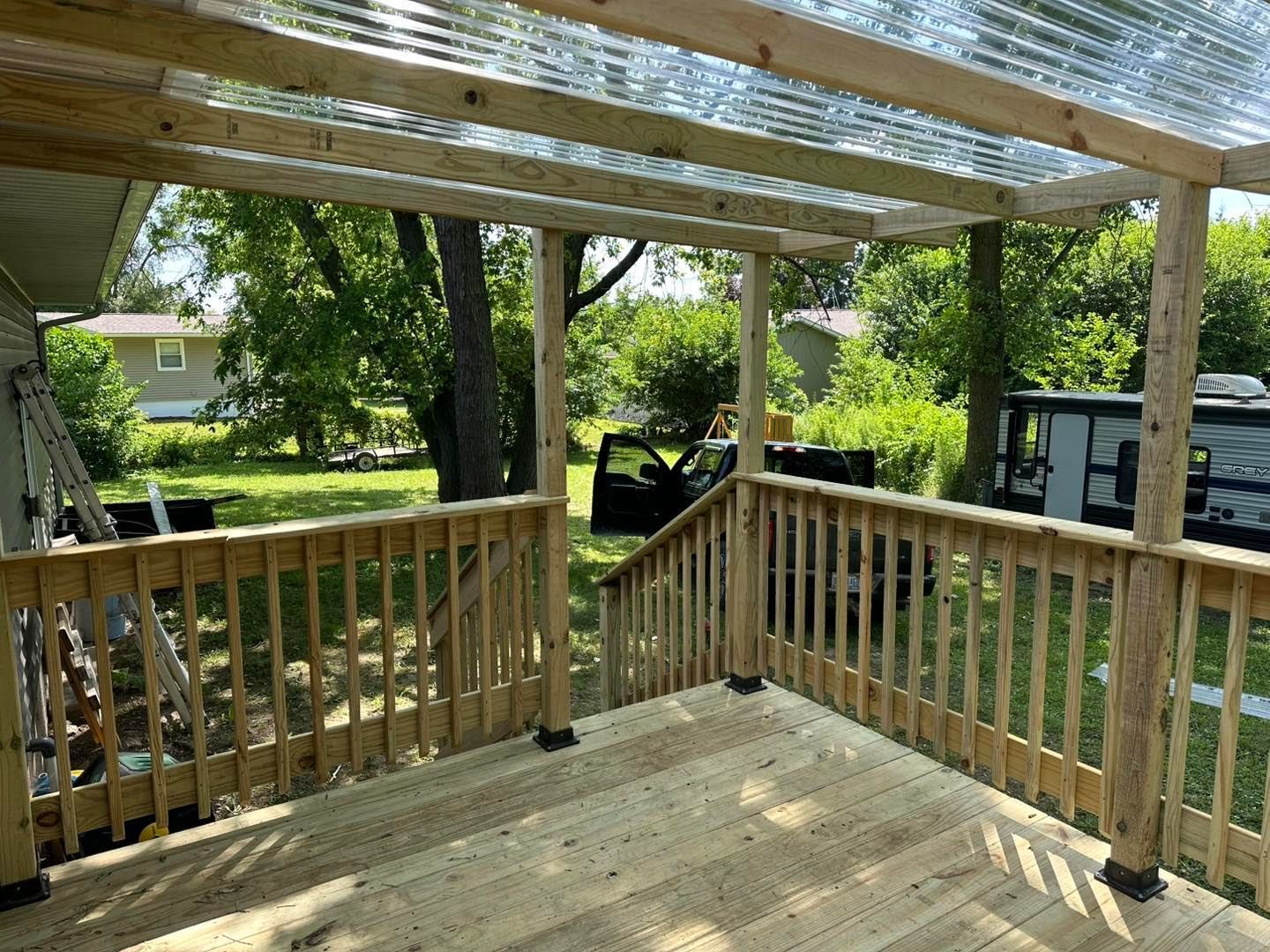A wooden deck with a clear plastic roof is being built.