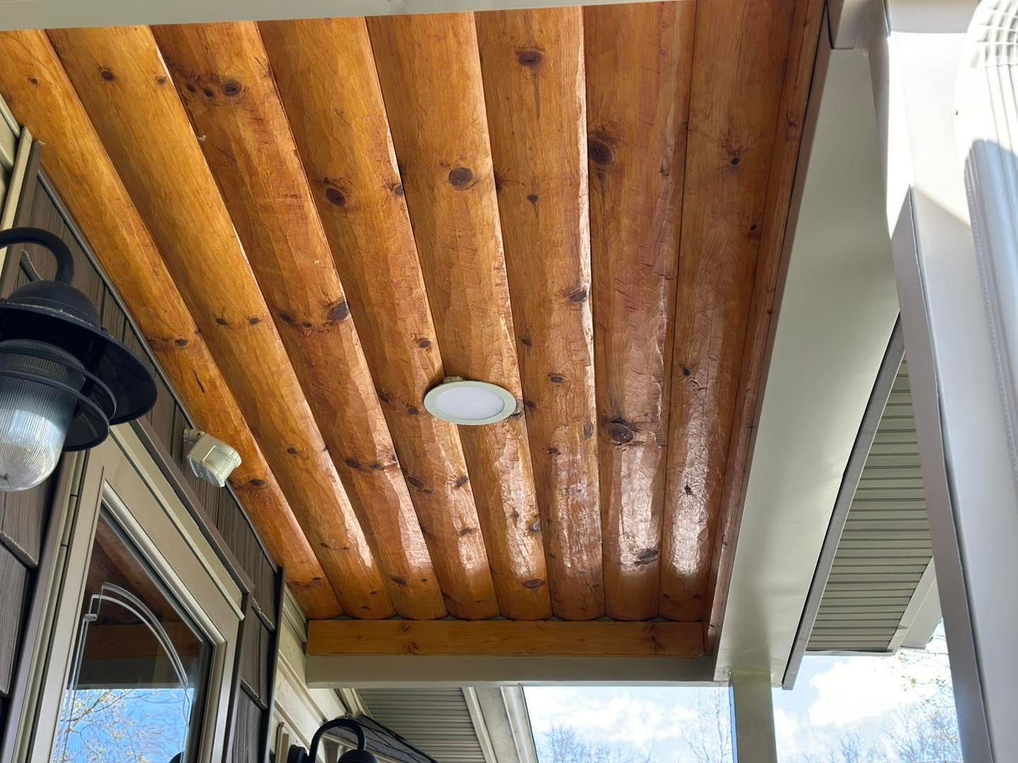 A porch with a wooden ceiling and a light on it.