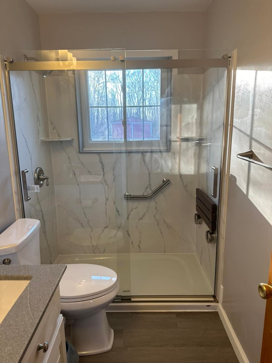 A bathroom with a toilet , sink , shower and window.