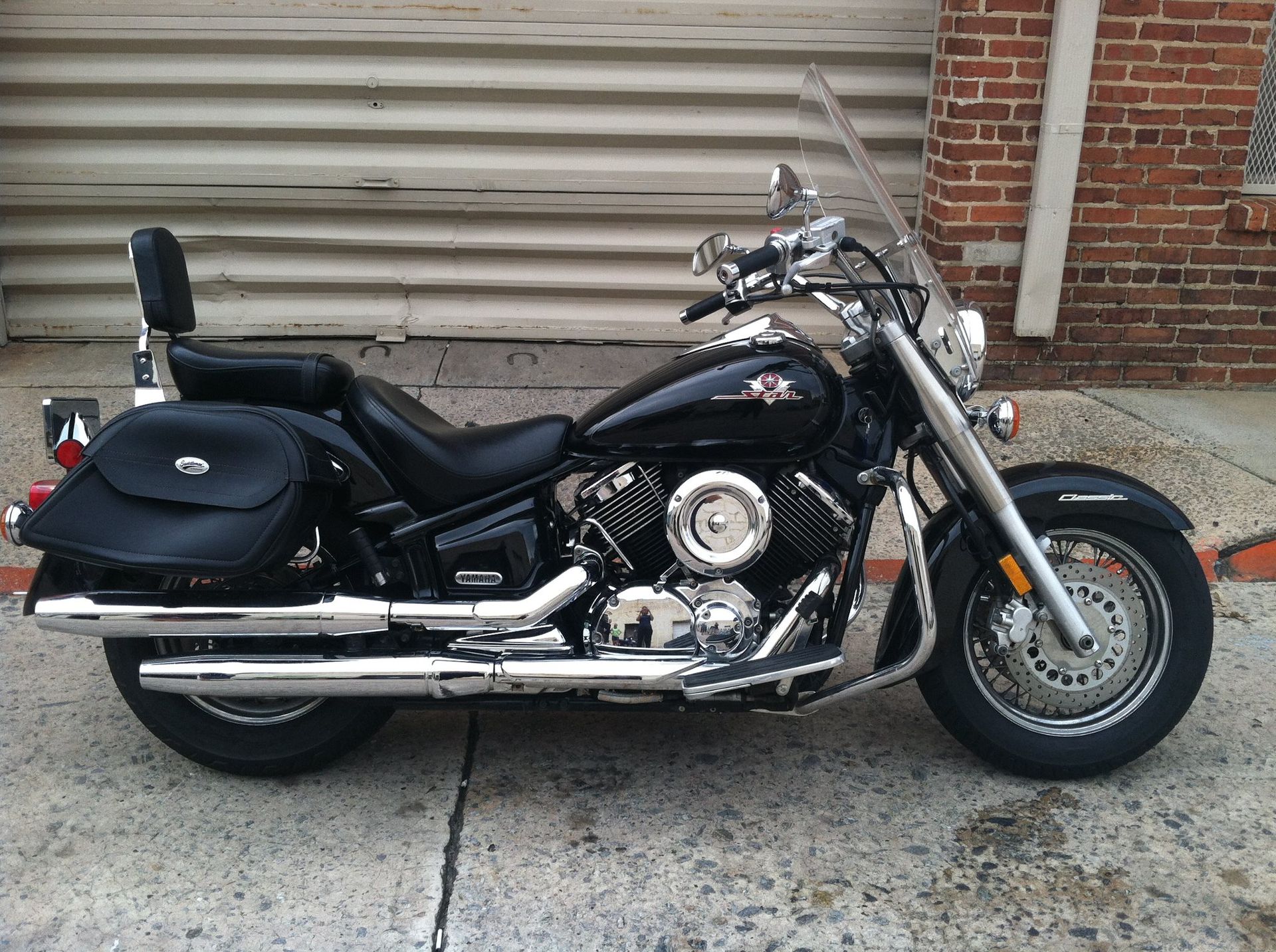 A black motorcycle is parked in front of a brick building.