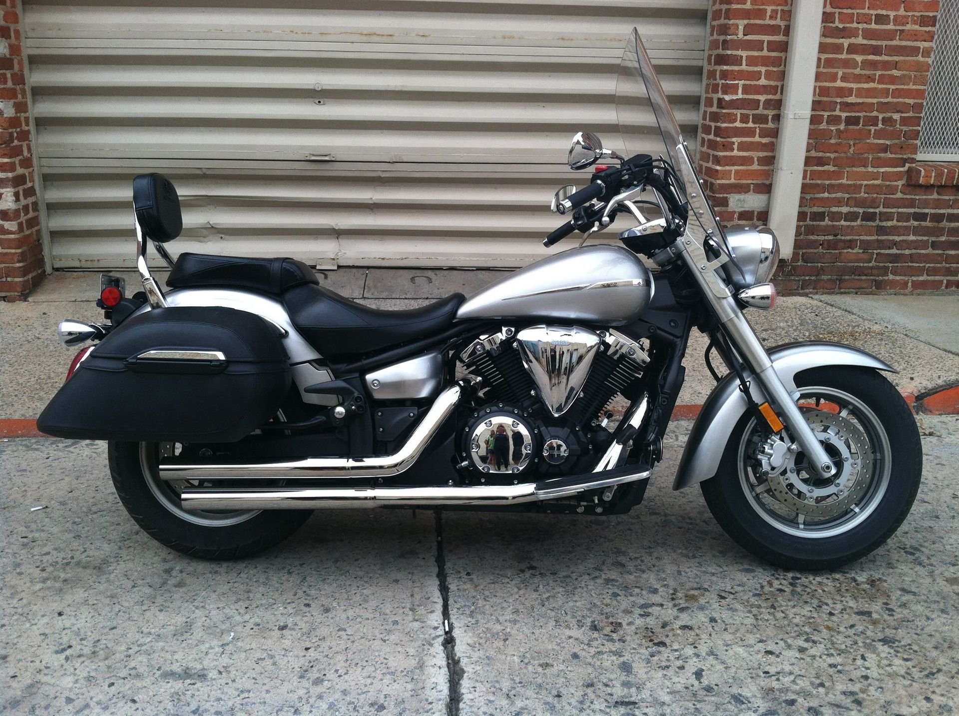 A silver and black motorcycle is parked in front of a brick building.