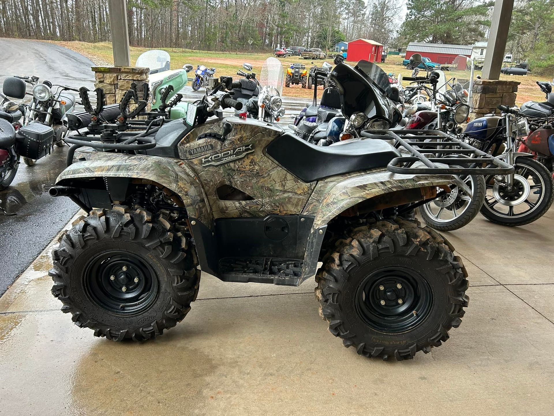 A large atv is parked in front of a row of motorcycles.