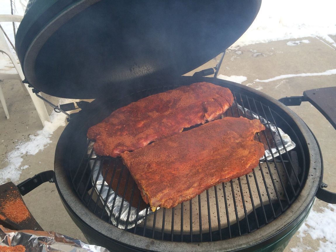 Two ribs are cooking on a grill with the lid open