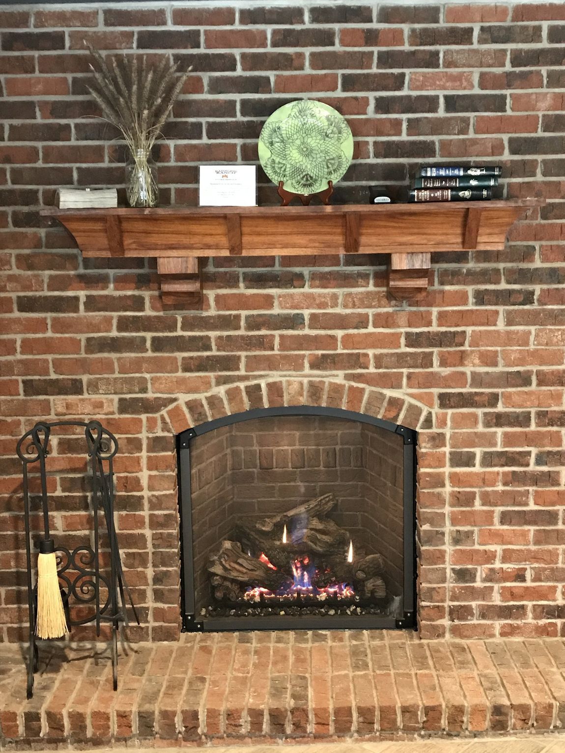 A brick fireplace with a wooden mantle in a living room.