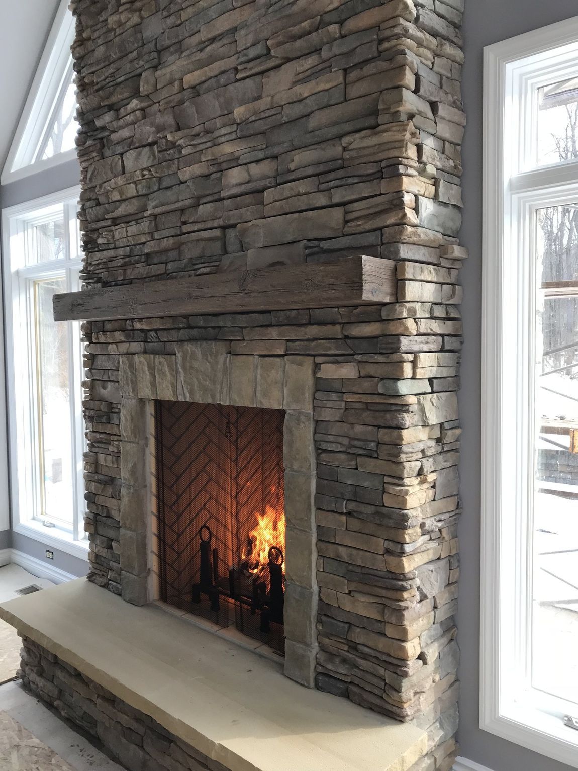 A large stone fireplace with a wooden mantle in a living room.