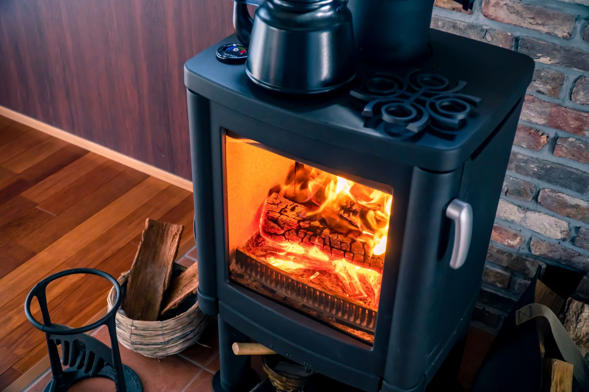 A wood stove is sitting in front of a brick wall in a living room.