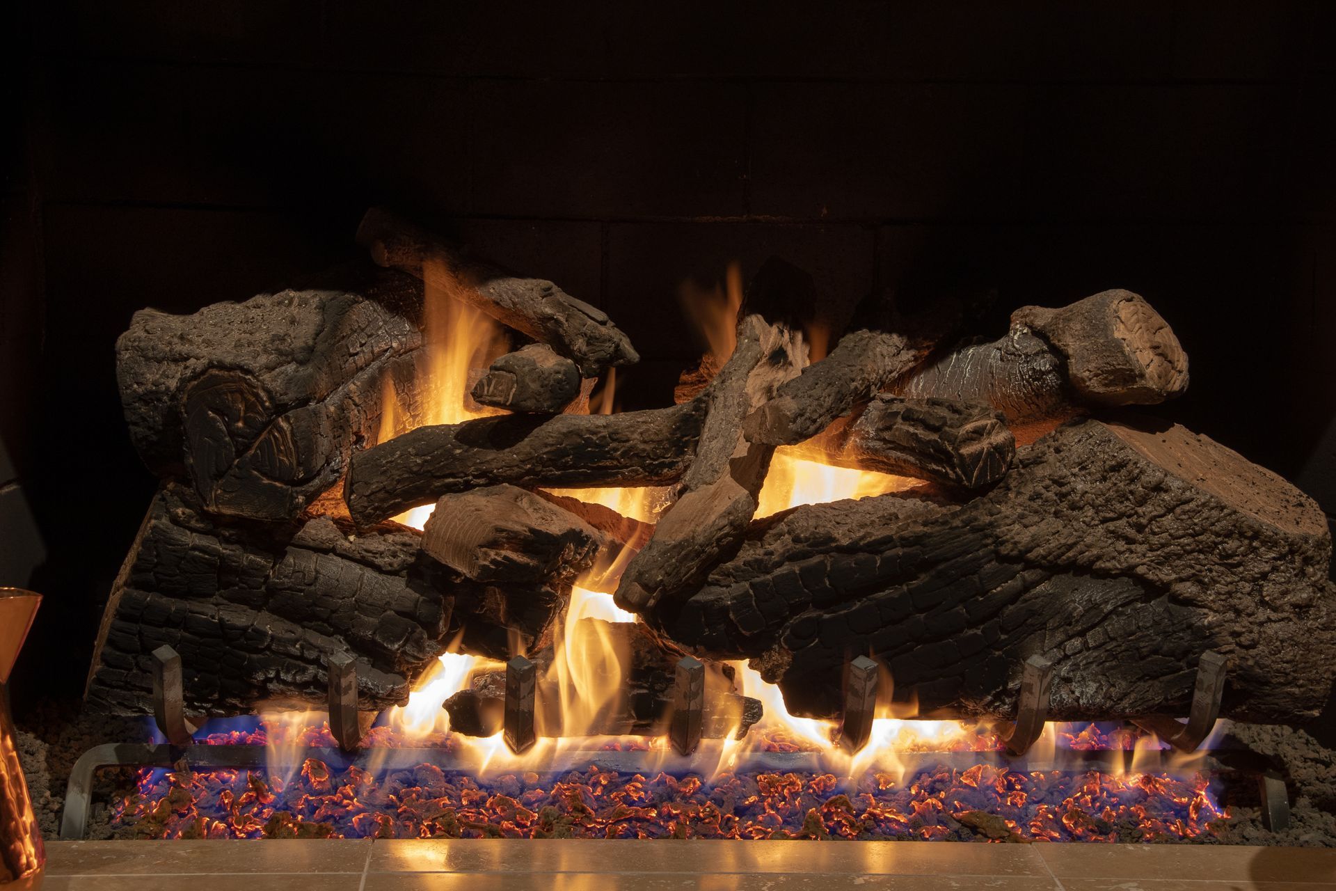 A fireplace with logs and flames coming out of it.