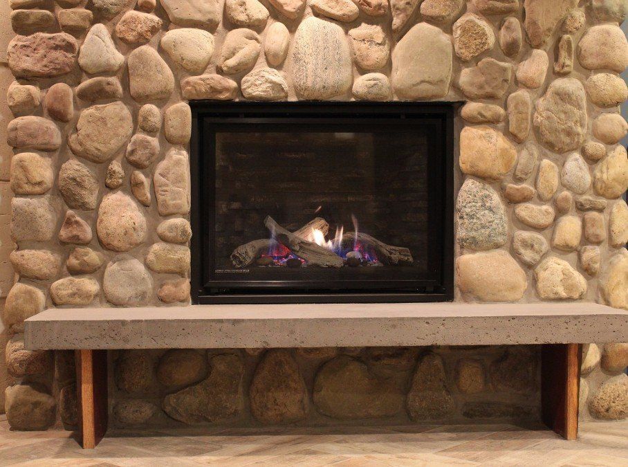 A fireplace with a stone wall and a bench in front of it
