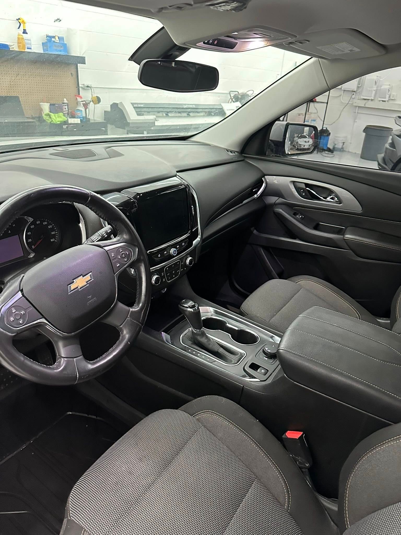 Woman in straw hat smiles, holding wine glass near a lake.