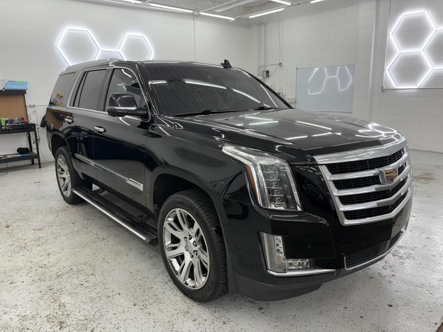 Woman in straw hat smiles, holding wine glass near a lake.