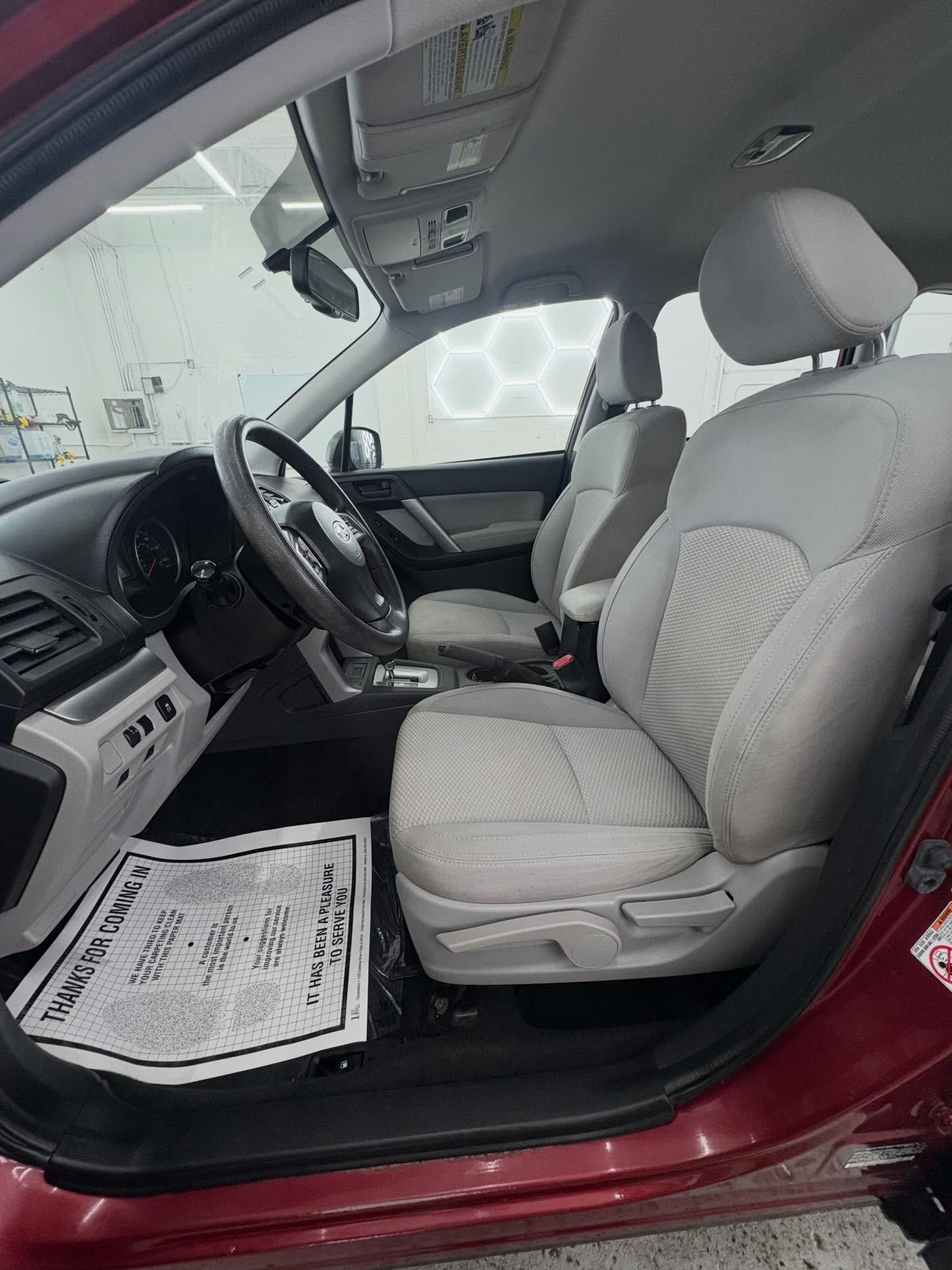 Woman in straw hat smiles, holding wine glass near a lake.