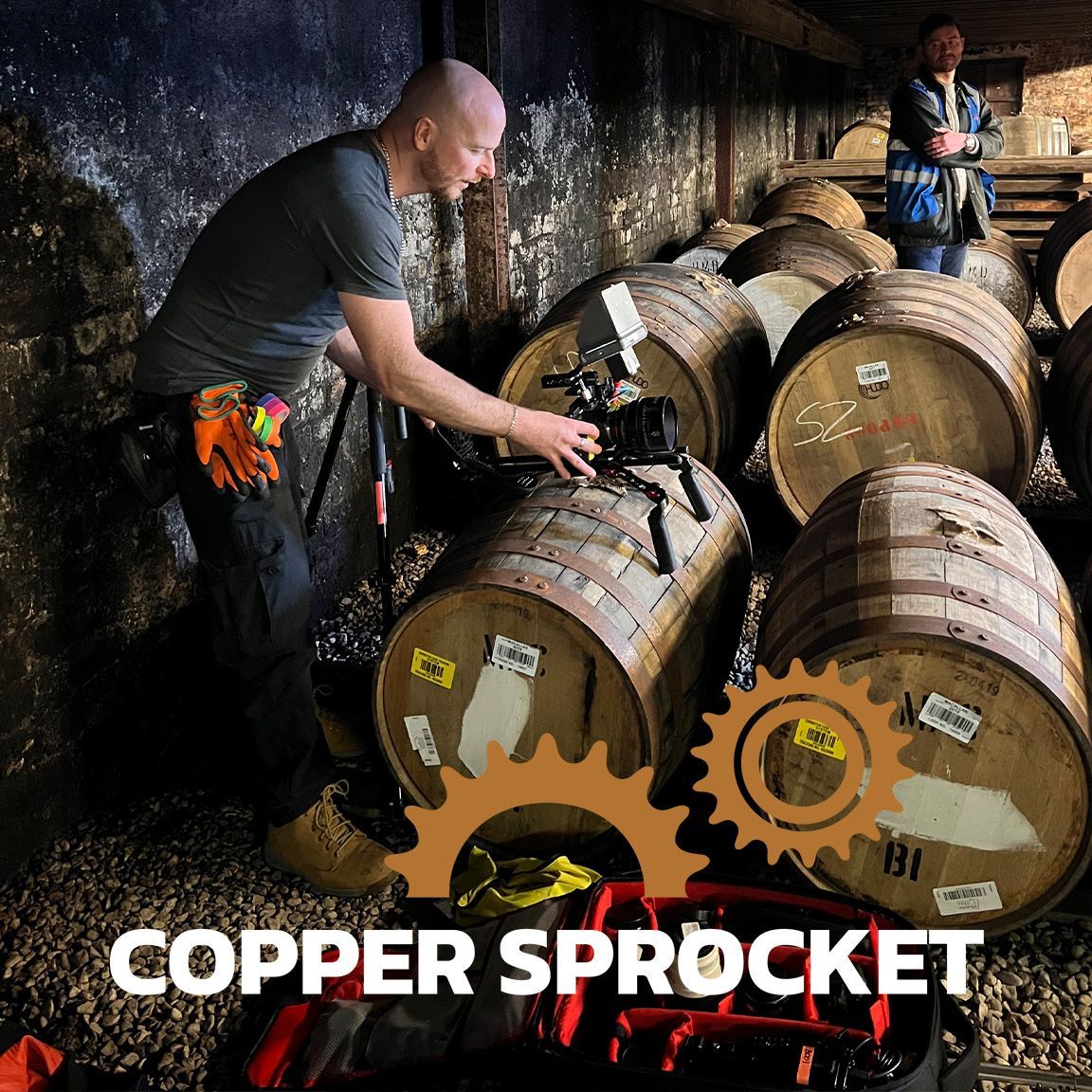 A videographer setting up a shot on top of whisky casks.