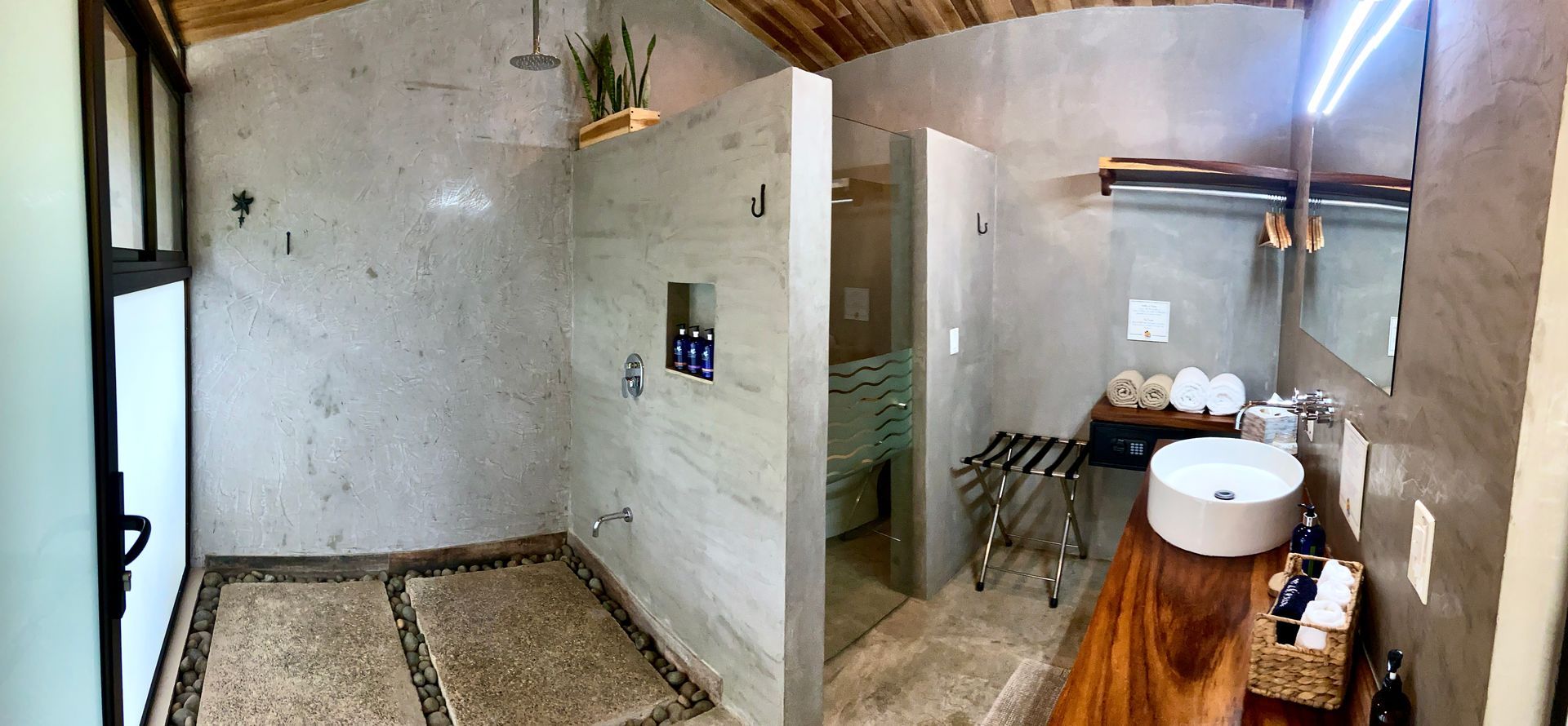Bathroom interior with stone shower, wooden counter, and large mirror.