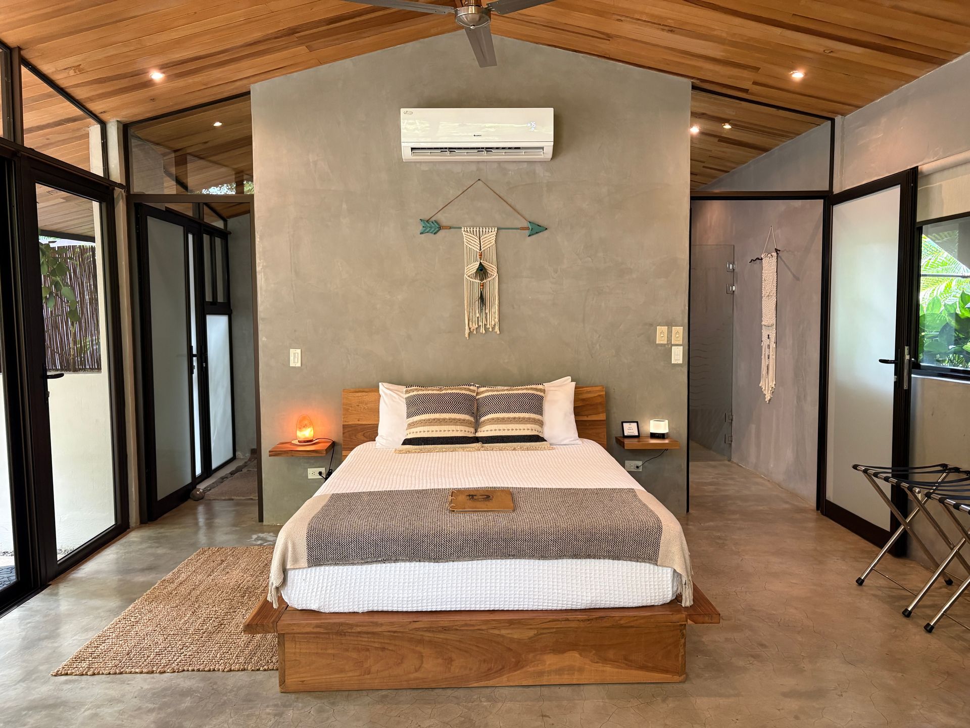 Bedroom with a wooden bed frame, grey wall, and glass doors.