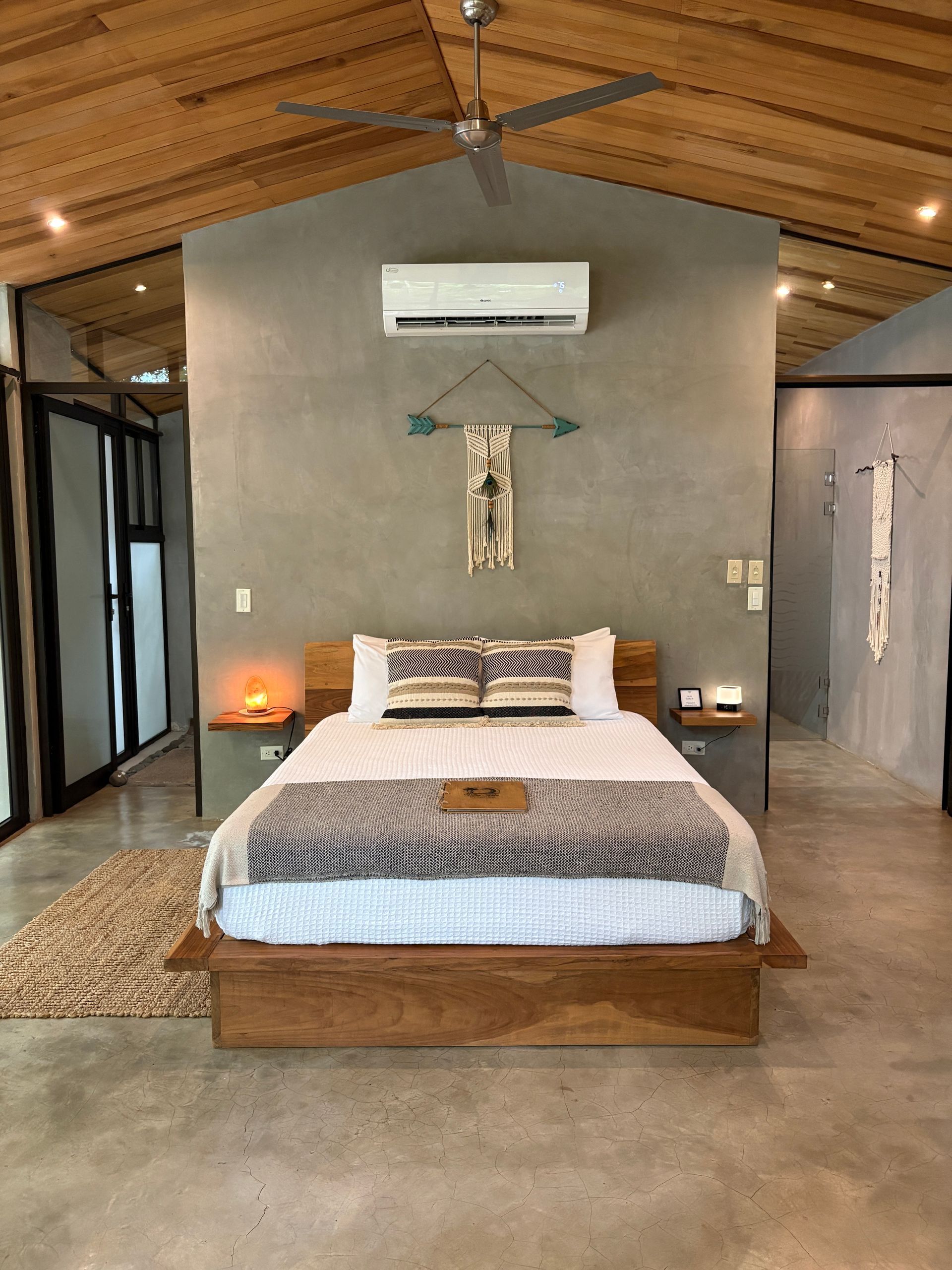 Bedroom with a wooden bed, gray wall, decor, and concrete floor.