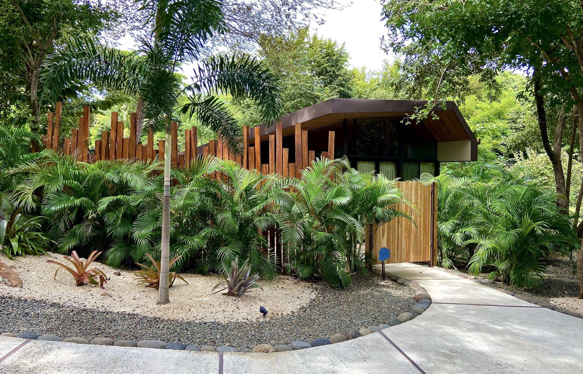 Modern home with wooden fence and lush landscaping, pathway leading to the entrance.
