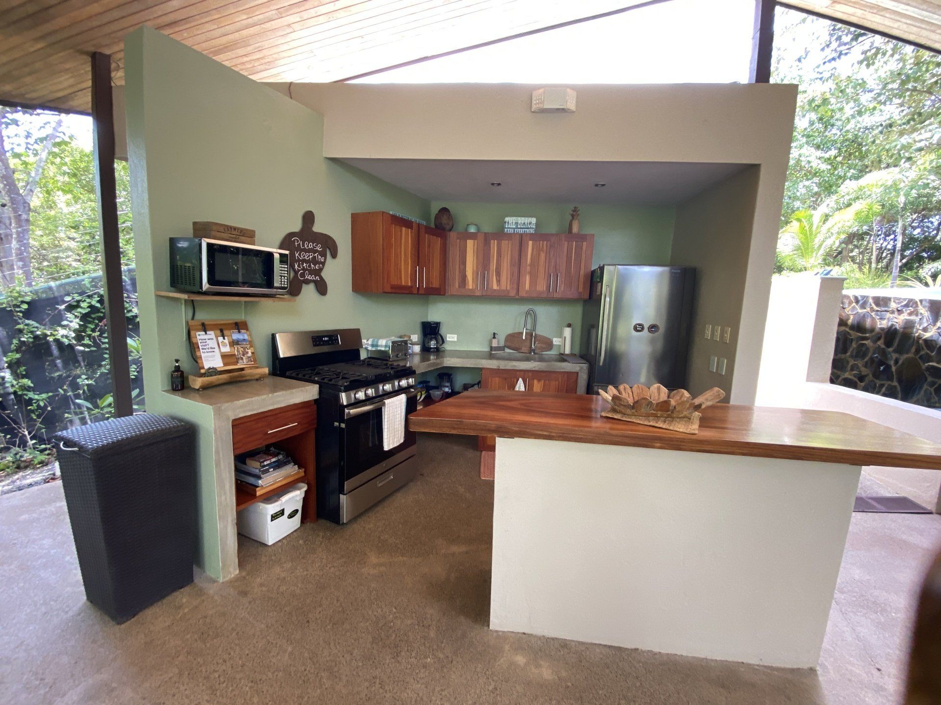 Outdoor kitchen with wood cabinets, stainless appliances, and a live-edge bar.