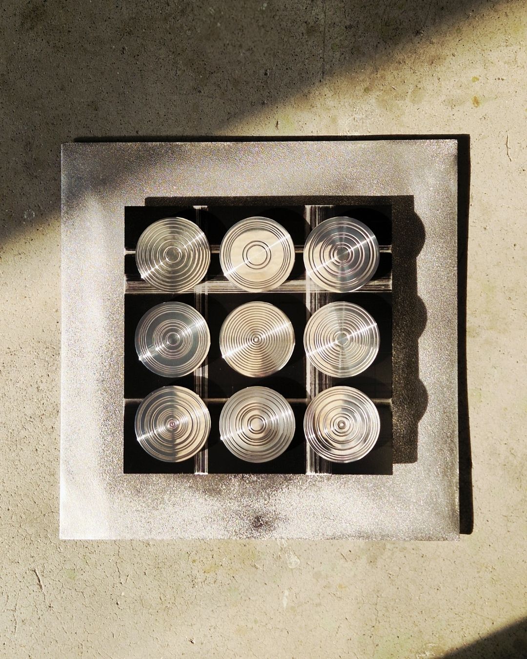 MOMENTI: PIASTRE IN ALLUMINIO FUSO SU LASTRA IN BRONZO OSSIDATO