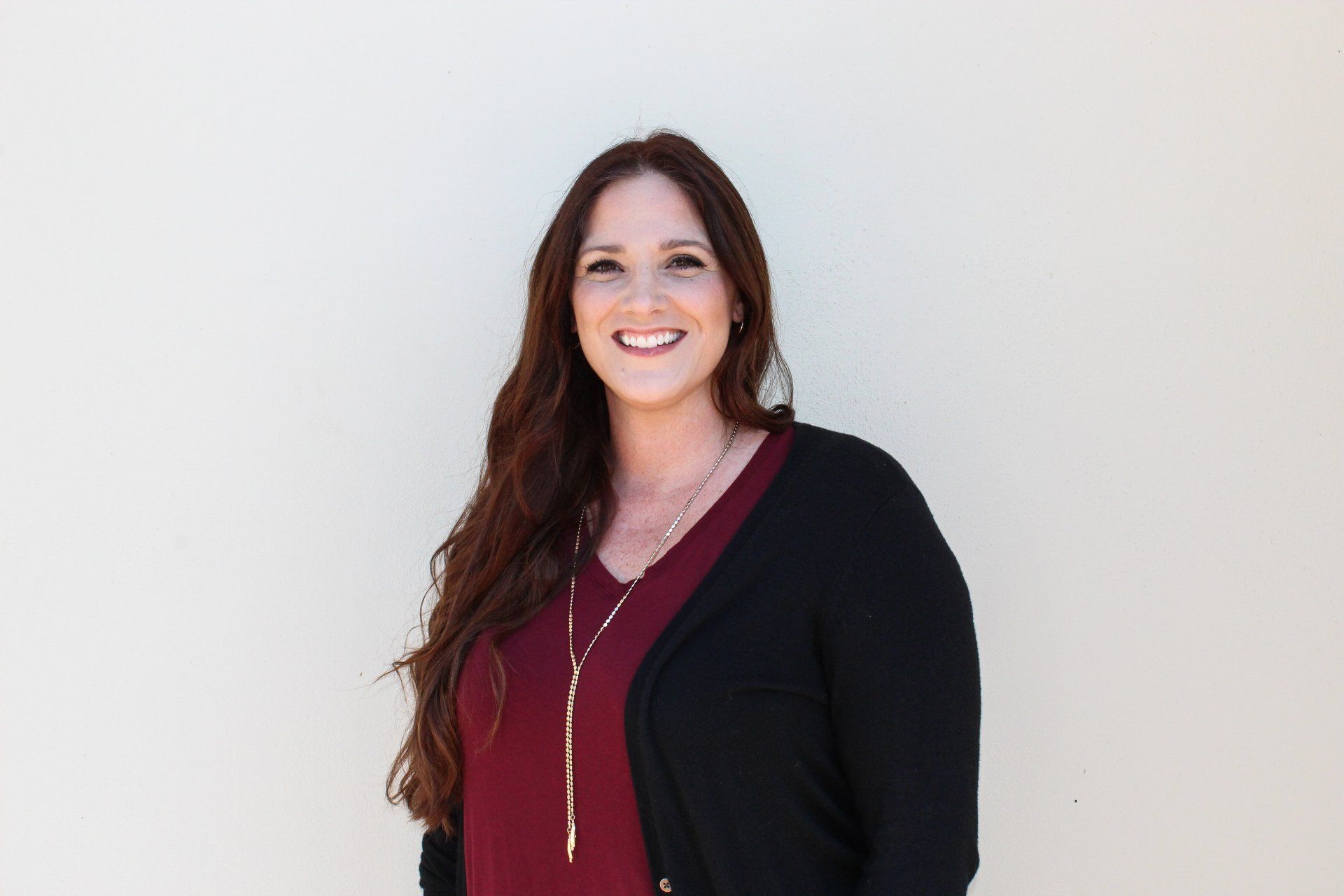 A woman wearing a black cardigan and a red shirt is smiling for the camera.
