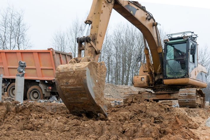 Excavator loading dirt into a dump truck at a construction site.