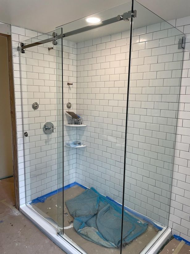 A shower stall with a sliding glass door is being built in a bathroom.