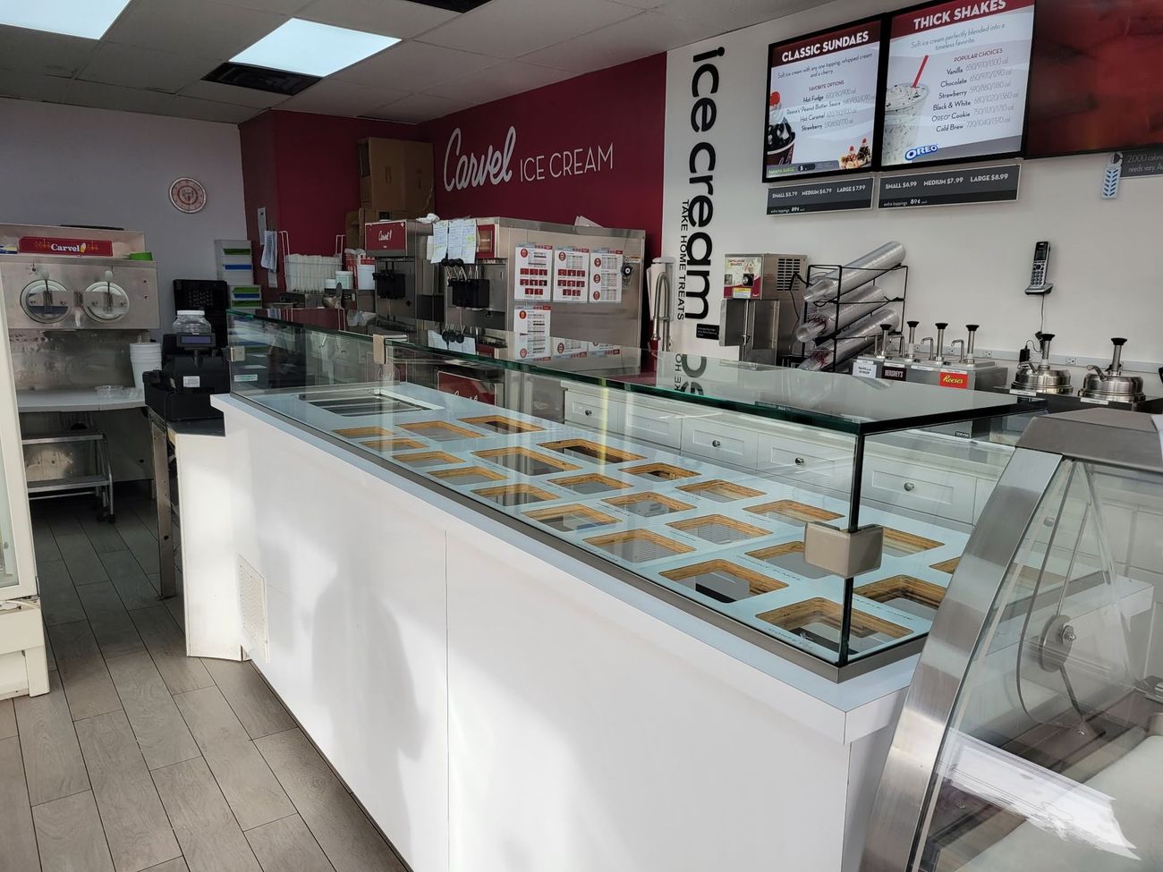 The inside of an ice cream shop with a glass display case filled with ice cream.