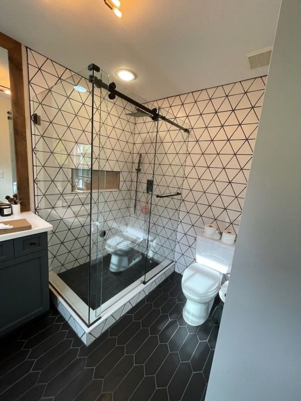 A bathroom with a walk in shower , toilet , sink and mirror.