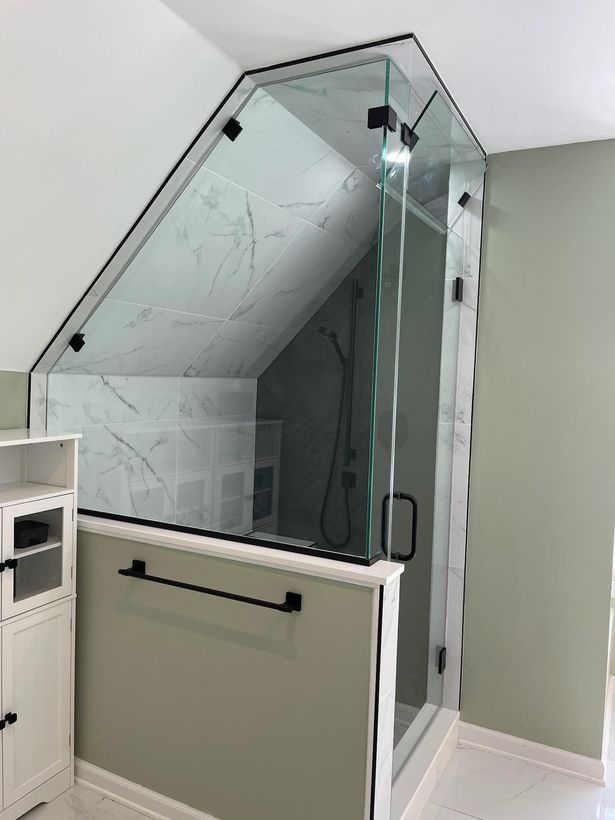 A bathroom with a slanted ceiling and a glass shower door.