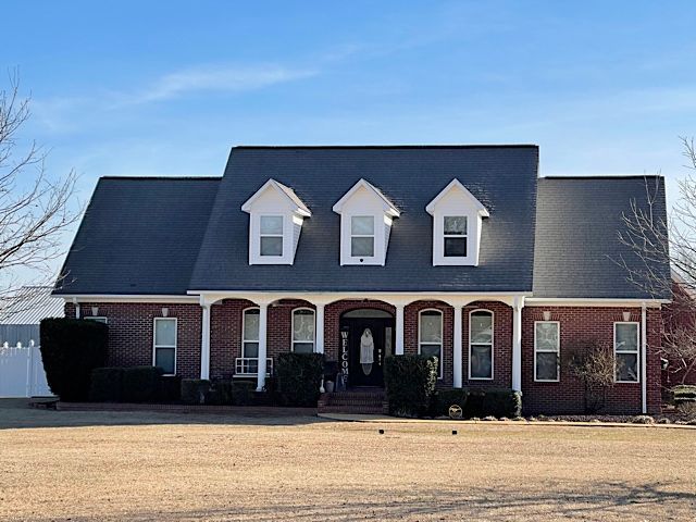 A large brick house with a black roof and white trim