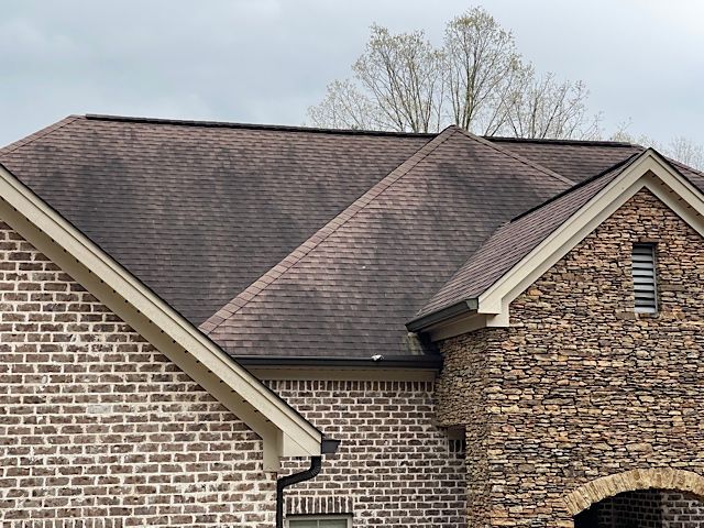 A brick house with a roof that is covered in moss.