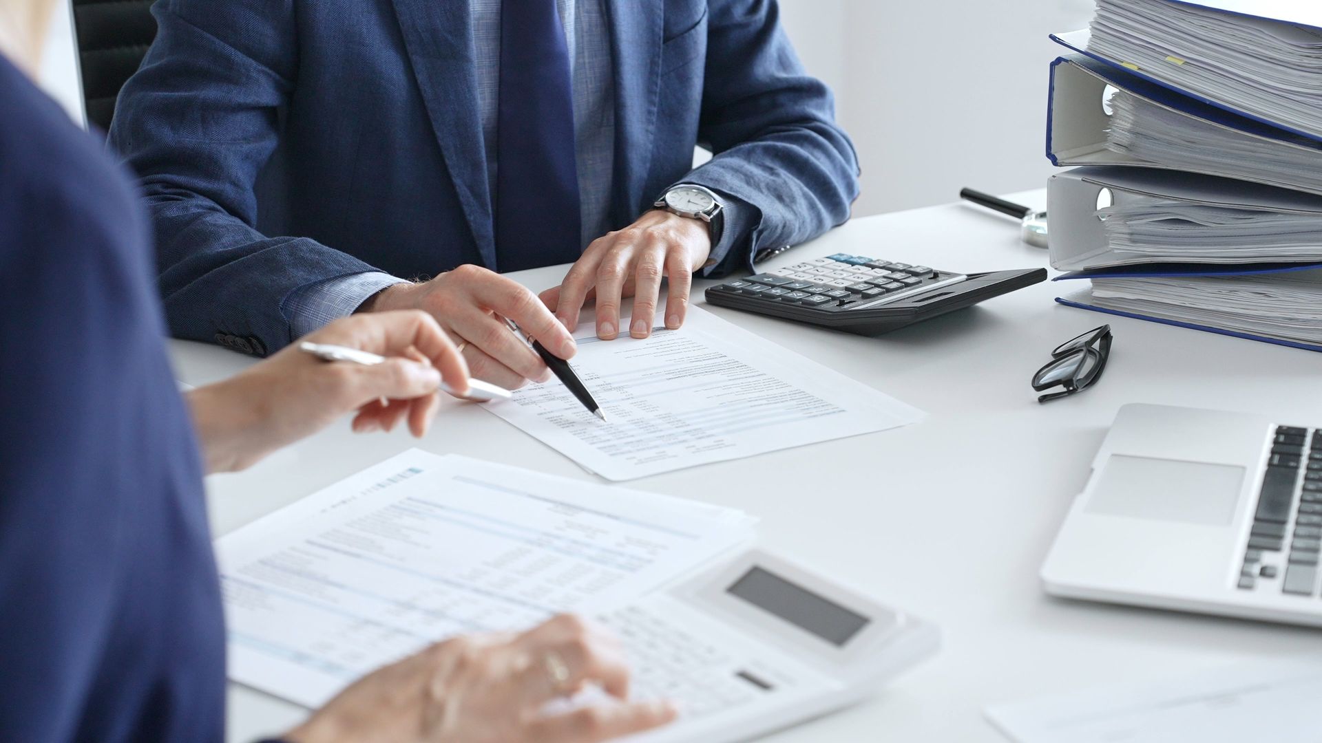 A professional financial advisor reviewing tax documents and budget reports with a client.