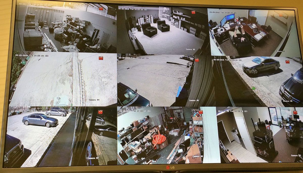 A surveillance monitor showing nine camera views: interior rooms, exterior parking, and walkways.