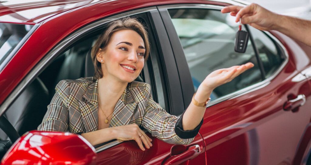 A rental car is parked beside the famous Puerto Princesa symbol as a young woman picks up the keys,